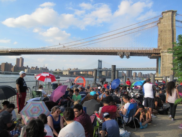 People waiting for Macy's 4th of July fireworks and having a picnic at Brooklyn Bridge Park in New York.